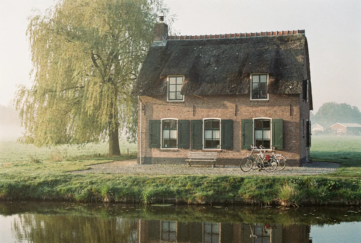 Rieten boerderij met treurwilg aan het water