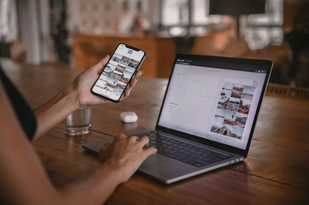 Website beheren op laptop en telefoon aan een houten tafel